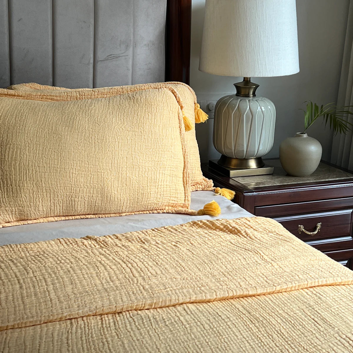 Woven bedspread in buttercup yellow with textured pattern and tassel accents.