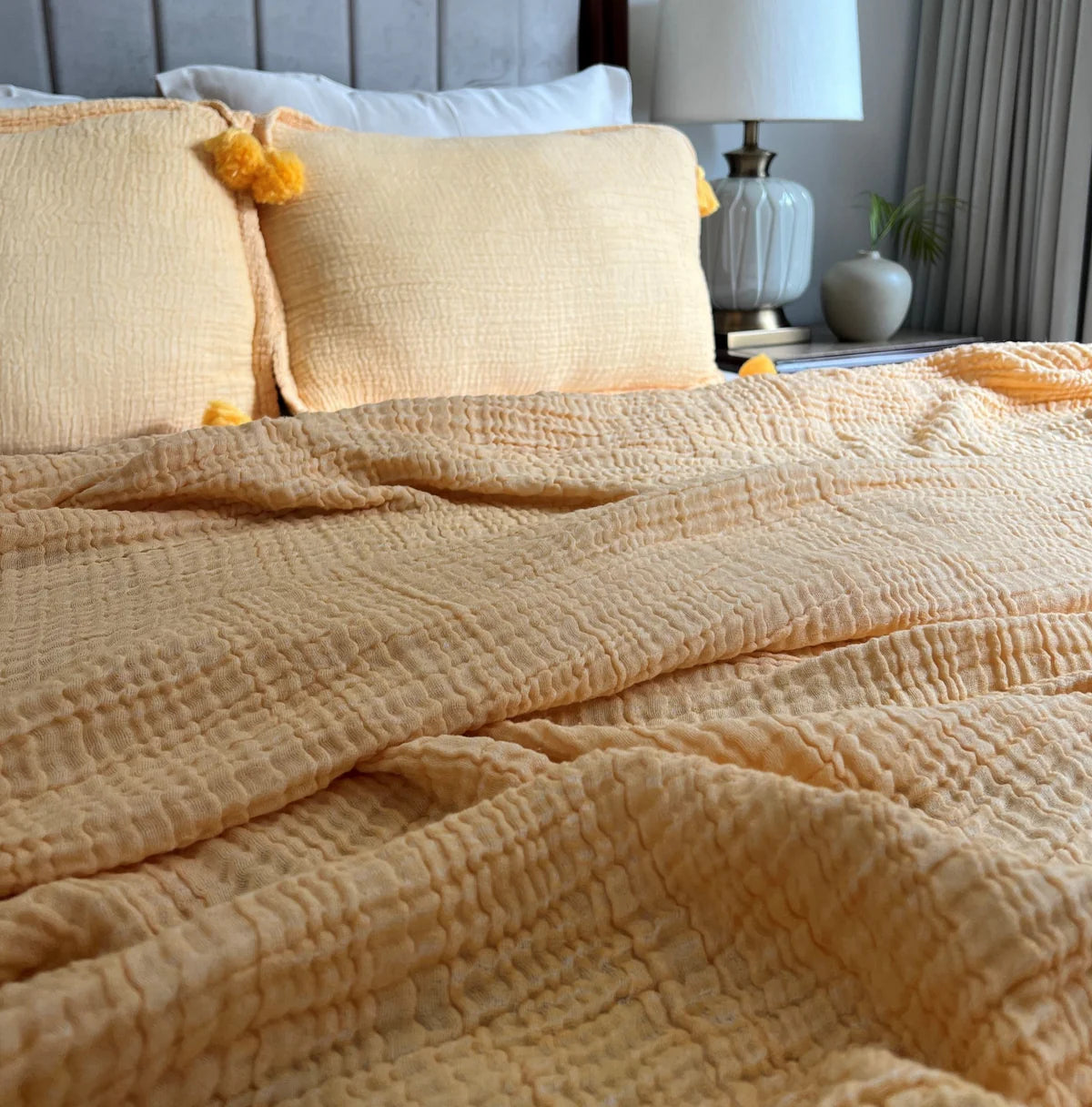 Buttercup yellow woven bedspread with crinkled texture and matching tassel pillows.
