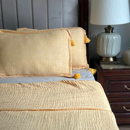 Buttercup yellow woven bedspread with textured pattern and tassels.