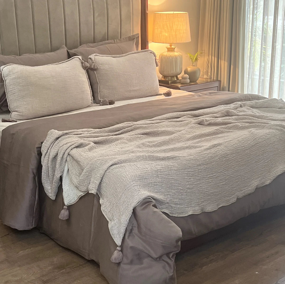 Buff woven bedspread with tassel pillows on bed.