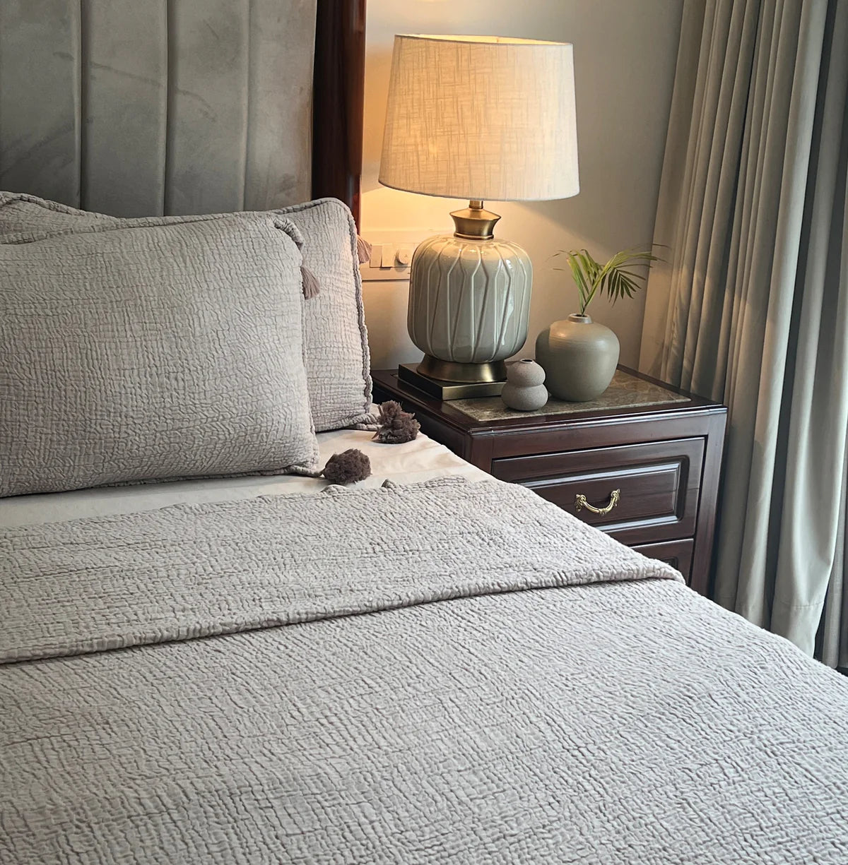 Textured woven bedspread with matching pillow shams on bed.