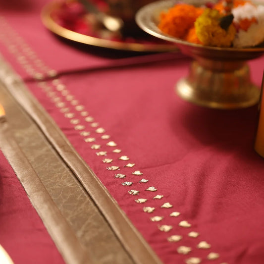 Maroon table runner with gold embroidery for dining decor.