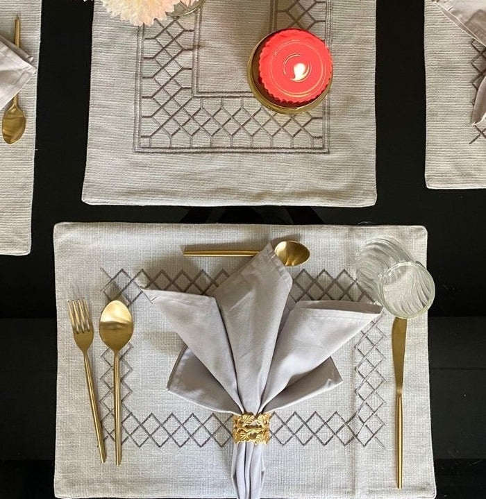 Stylish grey zigzag placemats with napkins and gold cutlery.