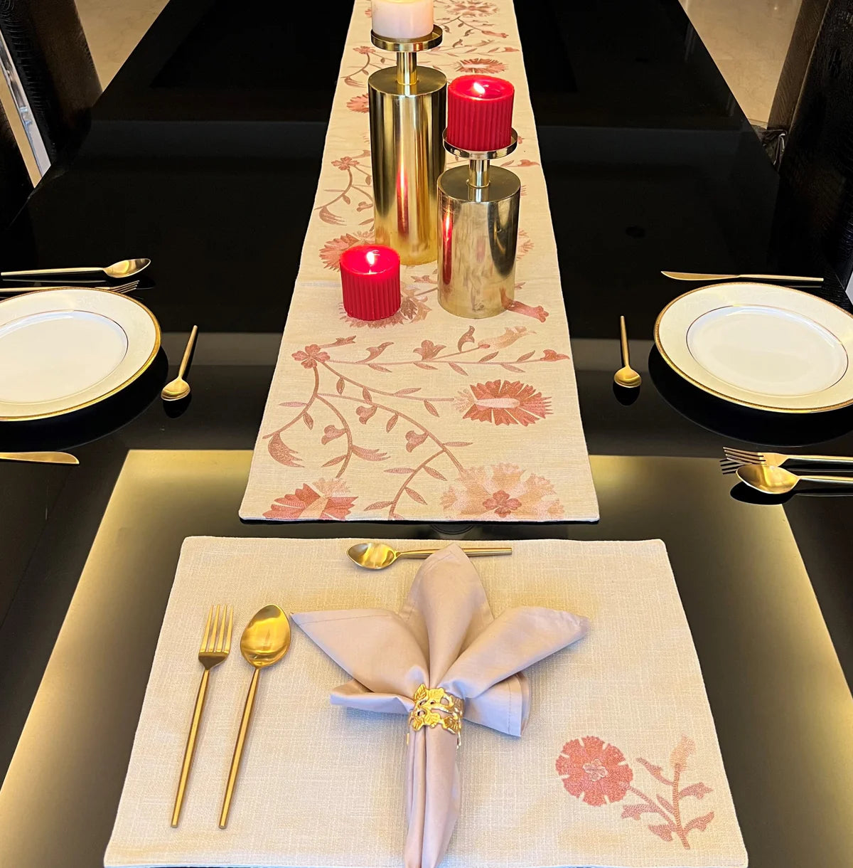 Elegant beige floral table linen set with runner and golden cutlery.