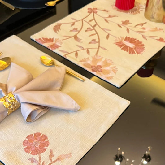 Elegant floral beige table linen with matching napkins and gold cutlery.