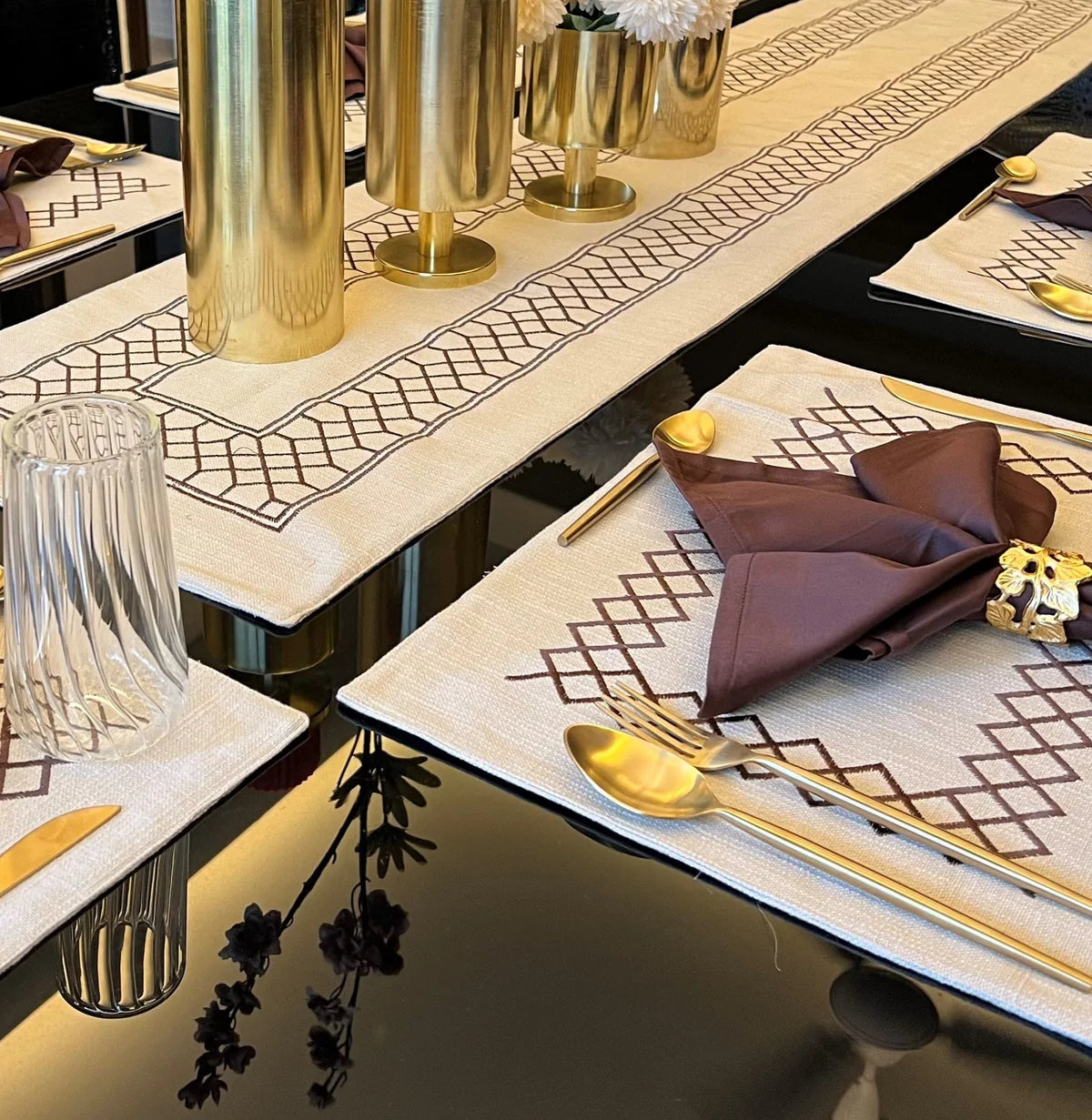 Beige zigzag table linen set with gold cutlery on a black table.