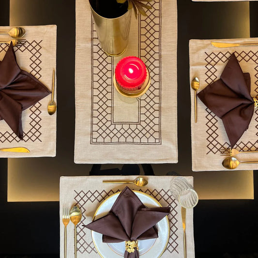 Elegant beige zigzag table linen set with brown napkins and gold cutlery.