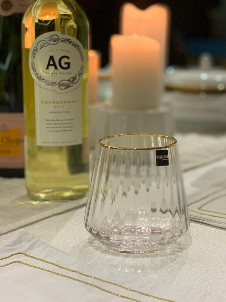 Elegant gold rimmed whiskey glass on a decorated table setting.