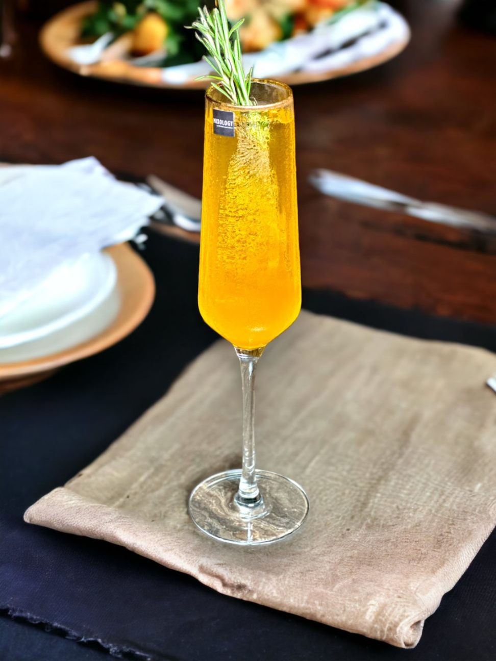 Close-up of cocktail glass; part of the Fitzgerald Champagne set with rosemary garnish.