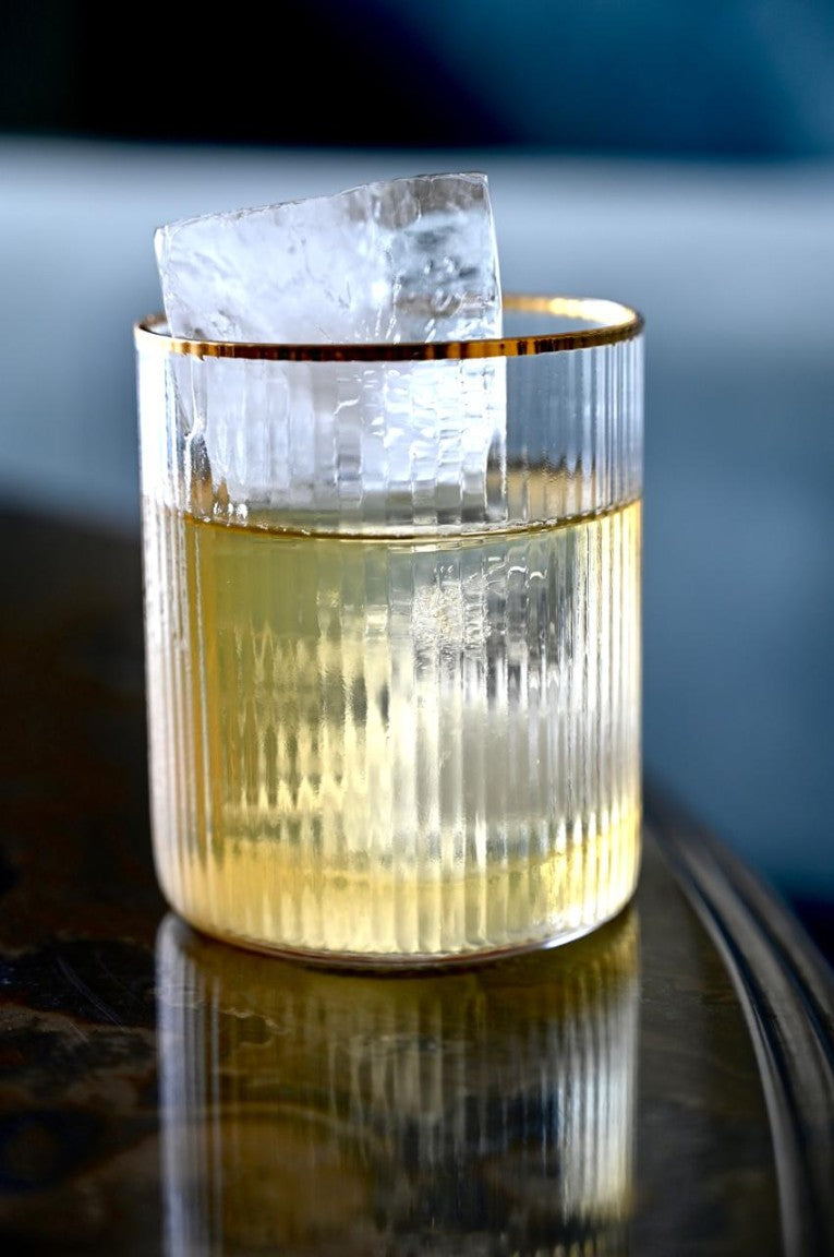 Ribbed glass with gold rim and ice, part of a glass set.