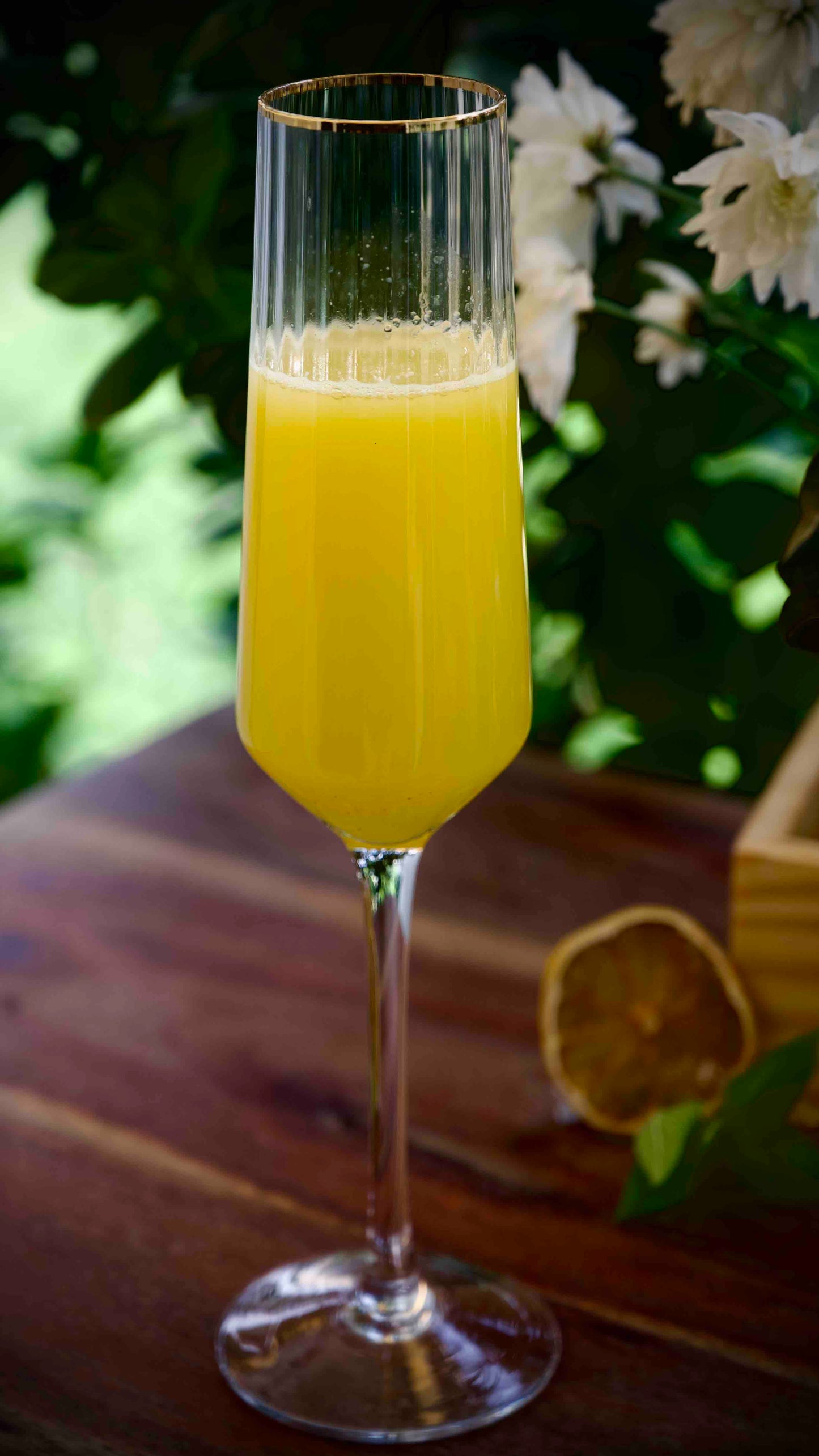 Elegant champagne glass with gold rim, filled with mimosa.