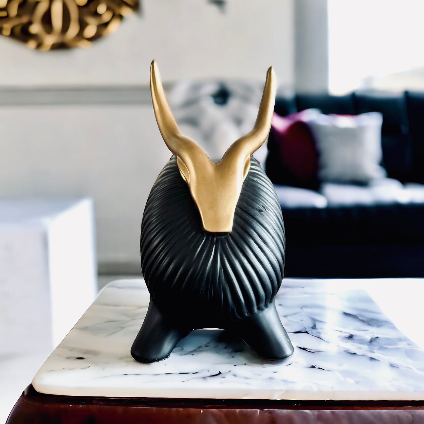 Black yak decor with gold horns on marble table.