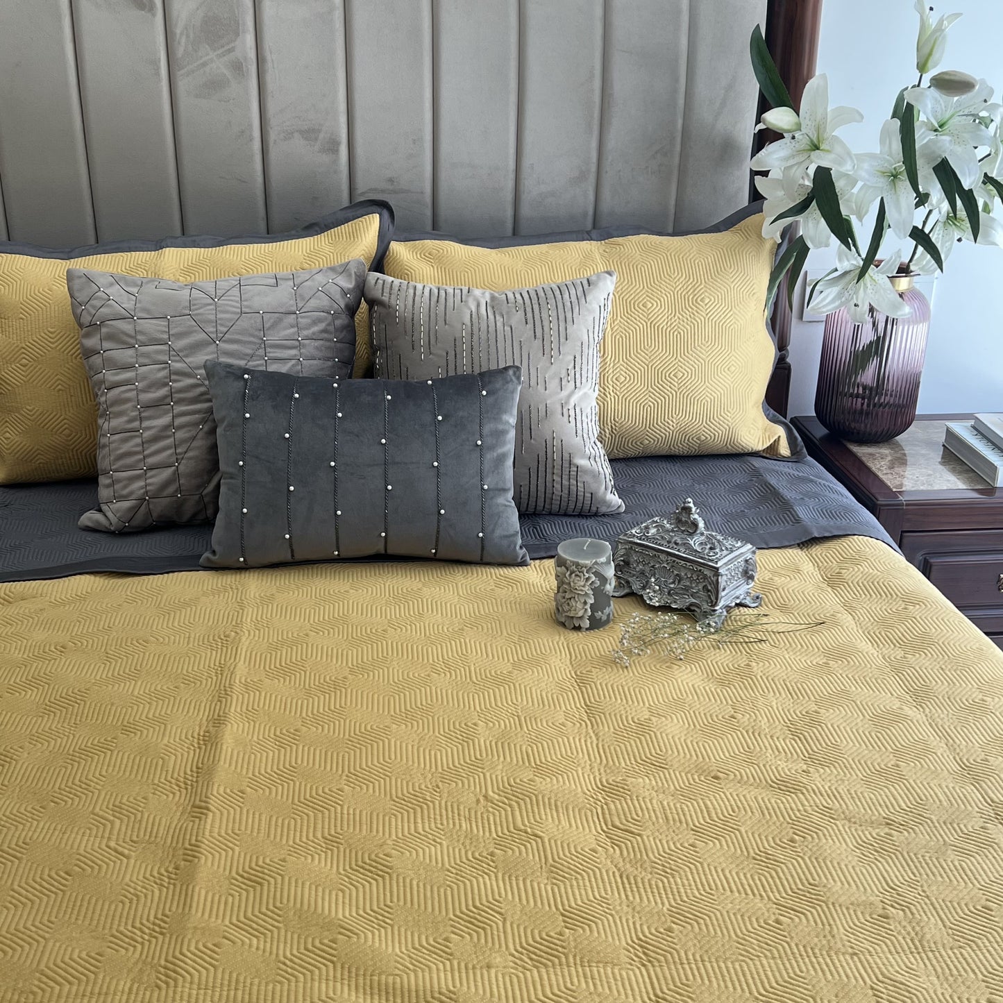 Buttercup yellow cotton bedspread with dark grey reversible side and pillows.