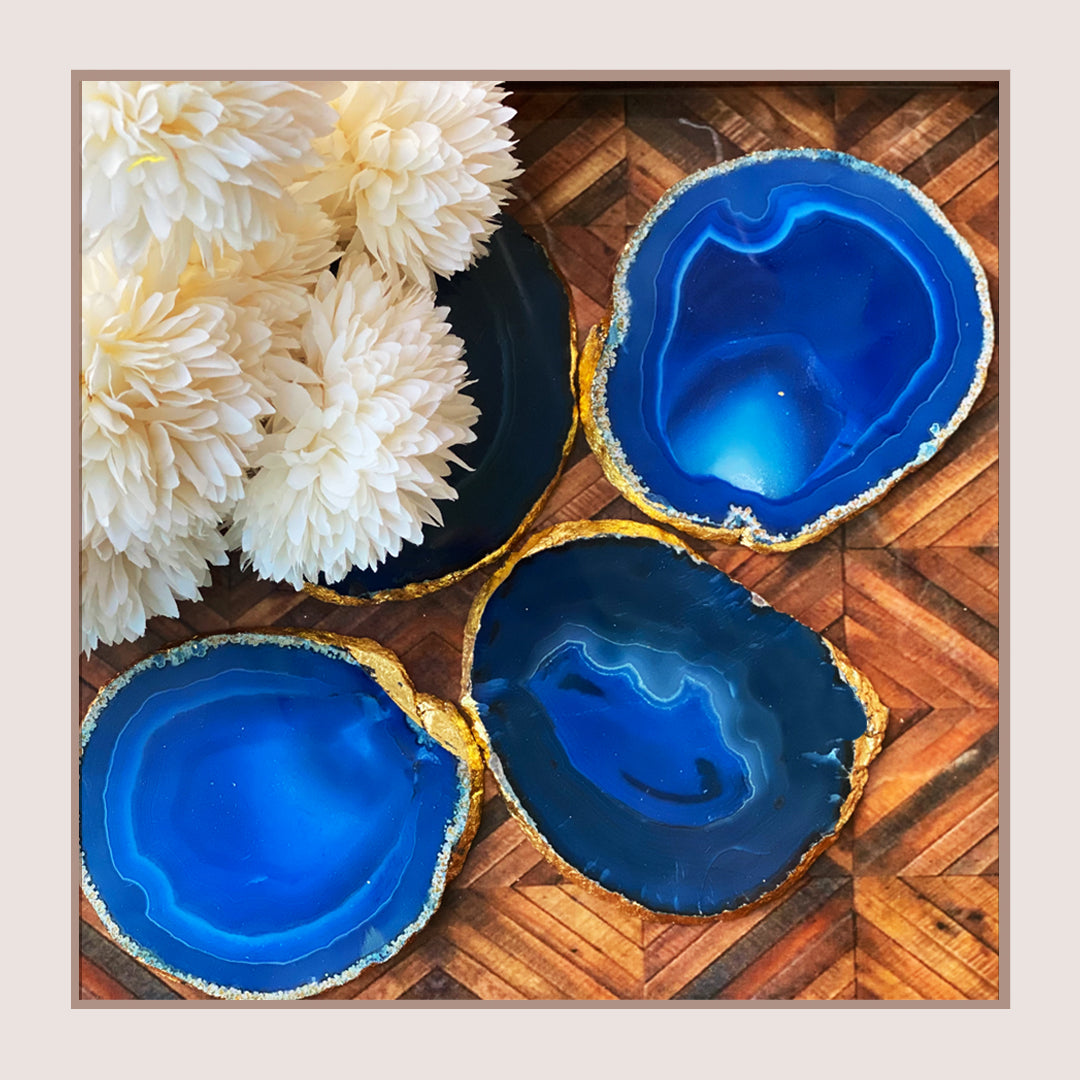 Set of four blue agate coasters with gold trim.