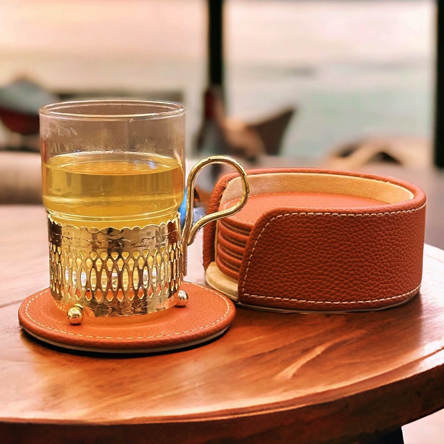 Cognac leather coasters set with drink on table; stitched leather design