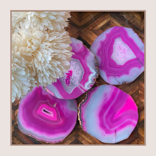 Set of four pink coasters with agate pattern and gold trim.