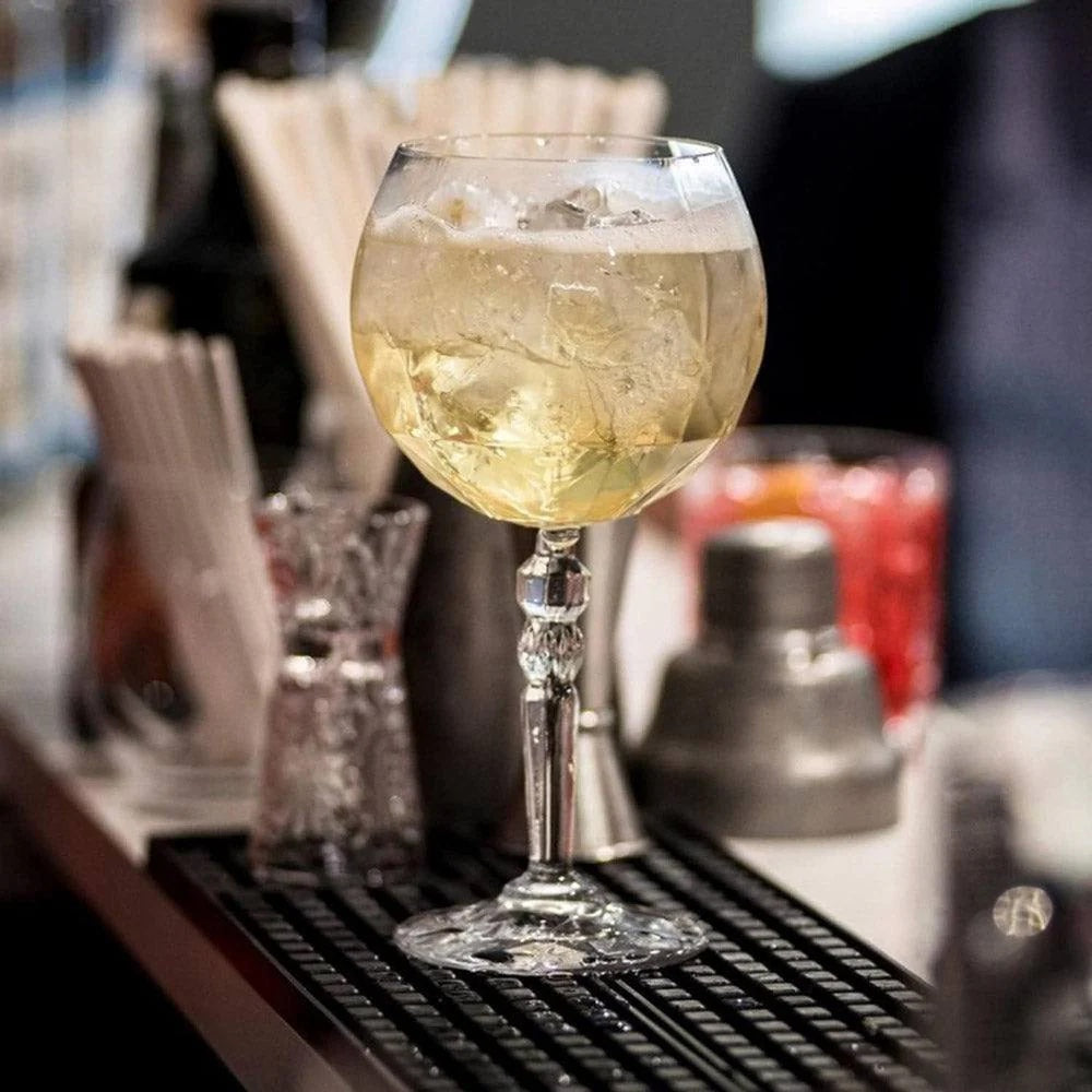 Elegant Alkemist gin tonic goblet with decorative stem on bar.