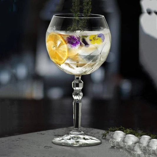 Gin and tonic goblet with orange and flowers, for stylish cocktails.