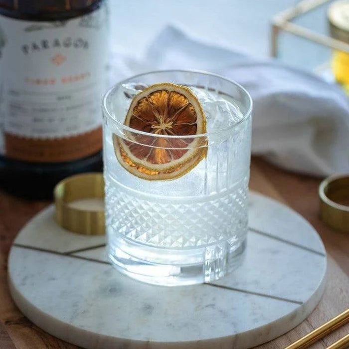 Brillante DOF tumbler with drink and orange slice on a marble coaster