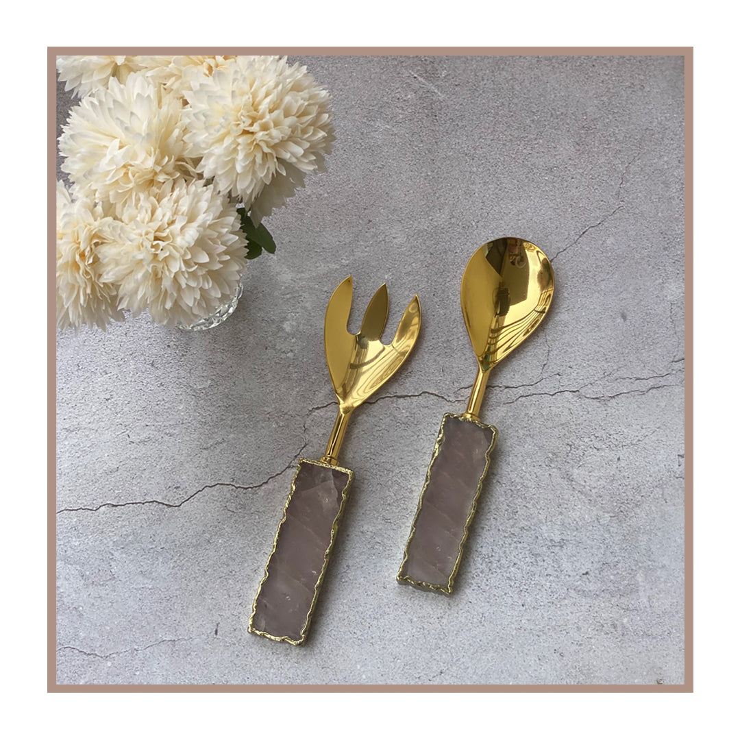 Shiny golden salad servers with rose quartz handles.