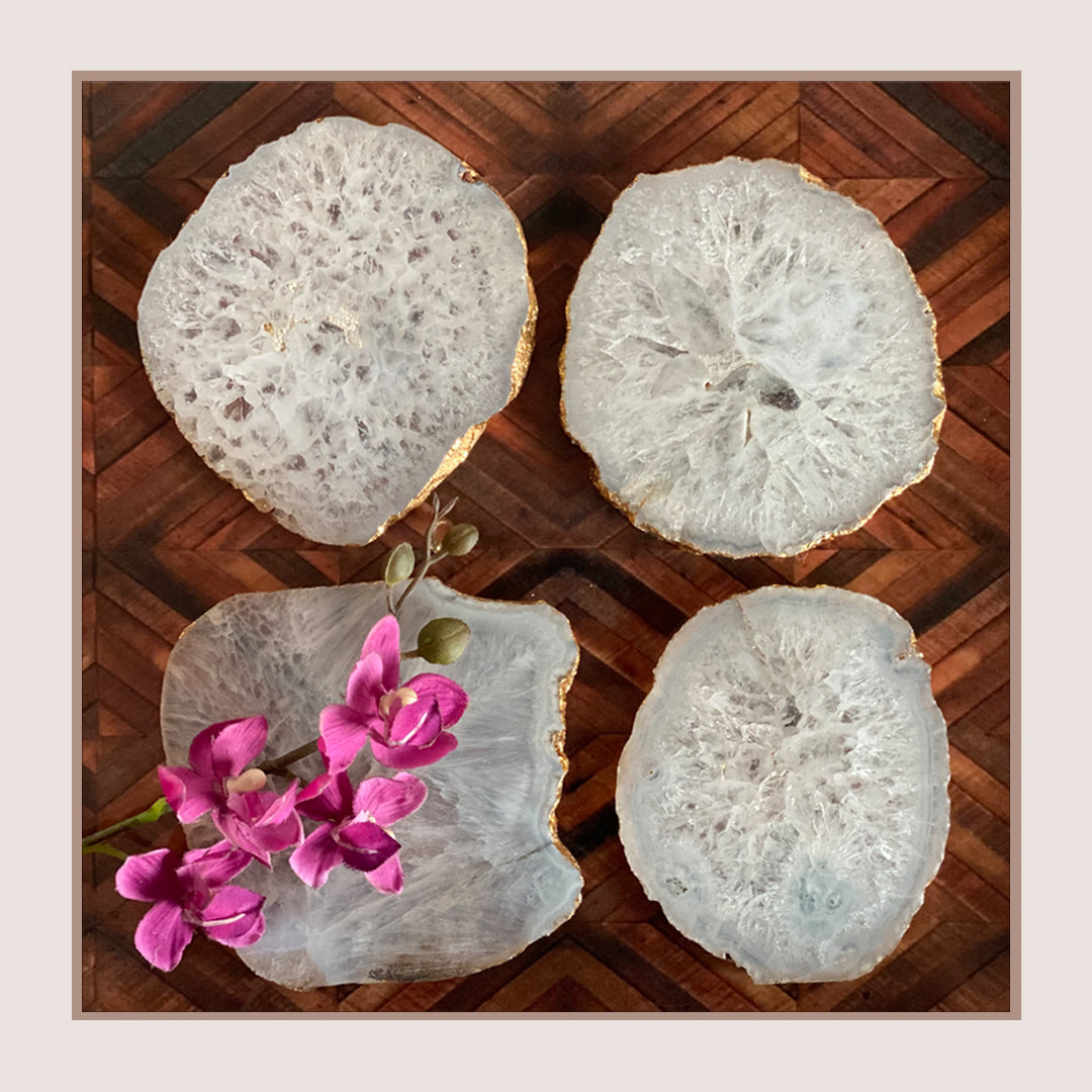 Set of four white agate coasters with gold trim detail.