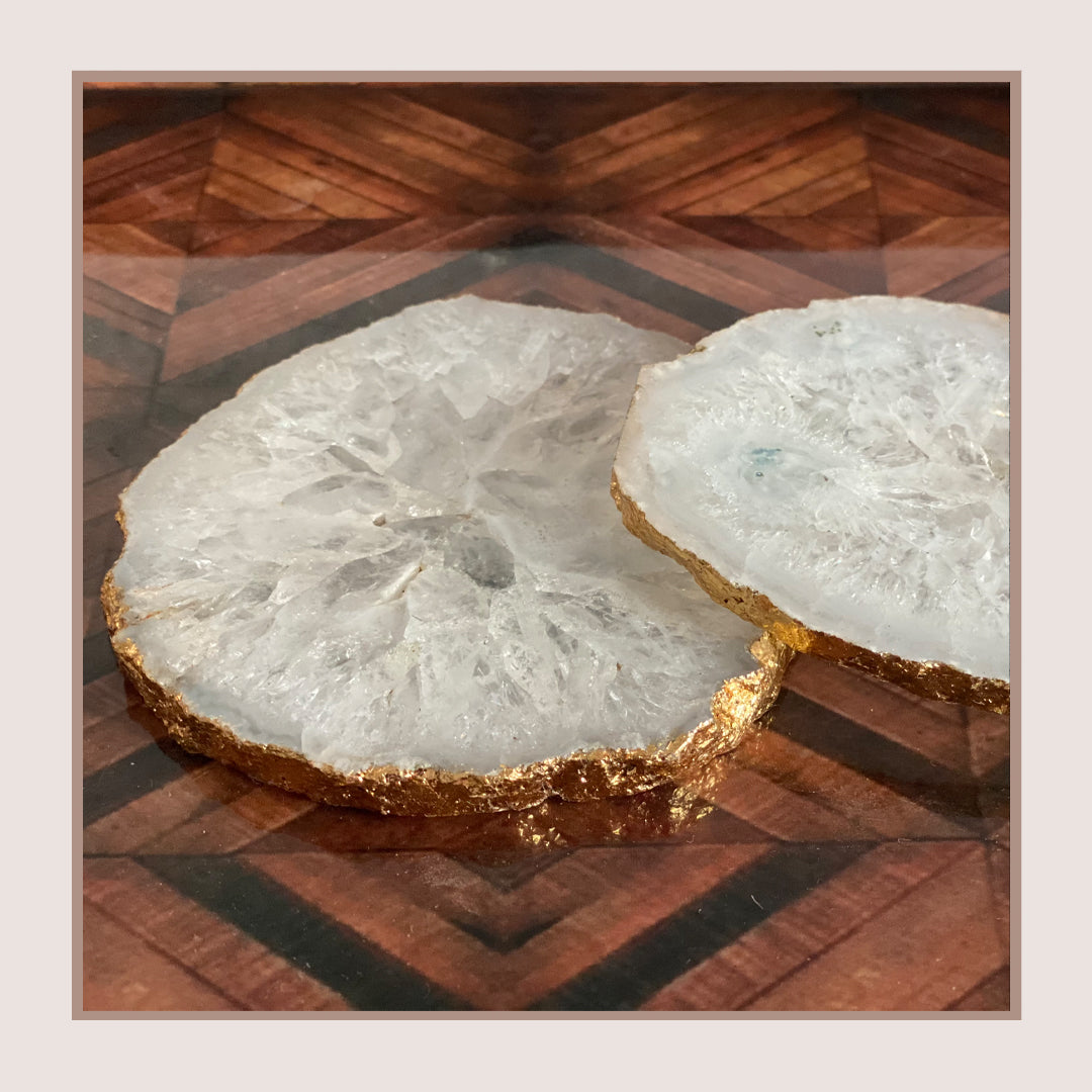 White agate coasters with gold trim on a wooden surface.