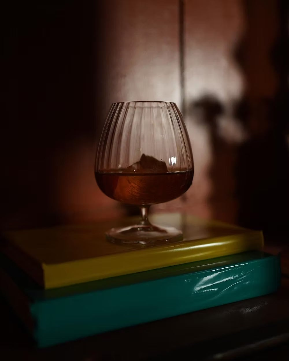 Luigi Bormioli mixology glass with liquor and ice on books.