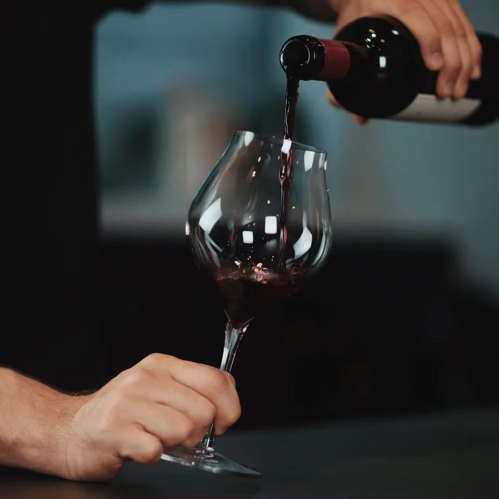 Pouring red wine into a Luigi Bormioli Amarone wine glass.