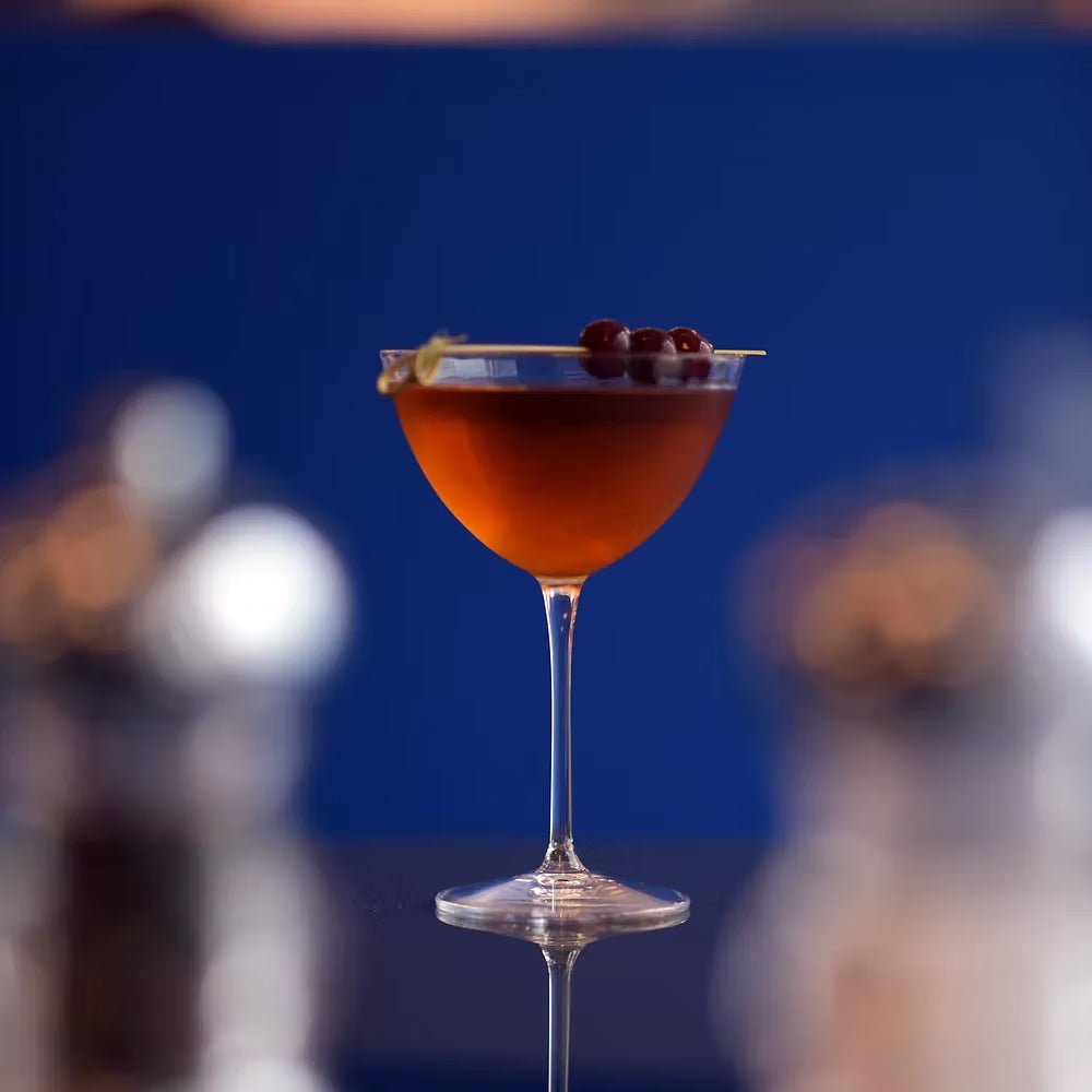 Stemmed Luigi Bormioli martini glass with cocktail and cherry garnish.