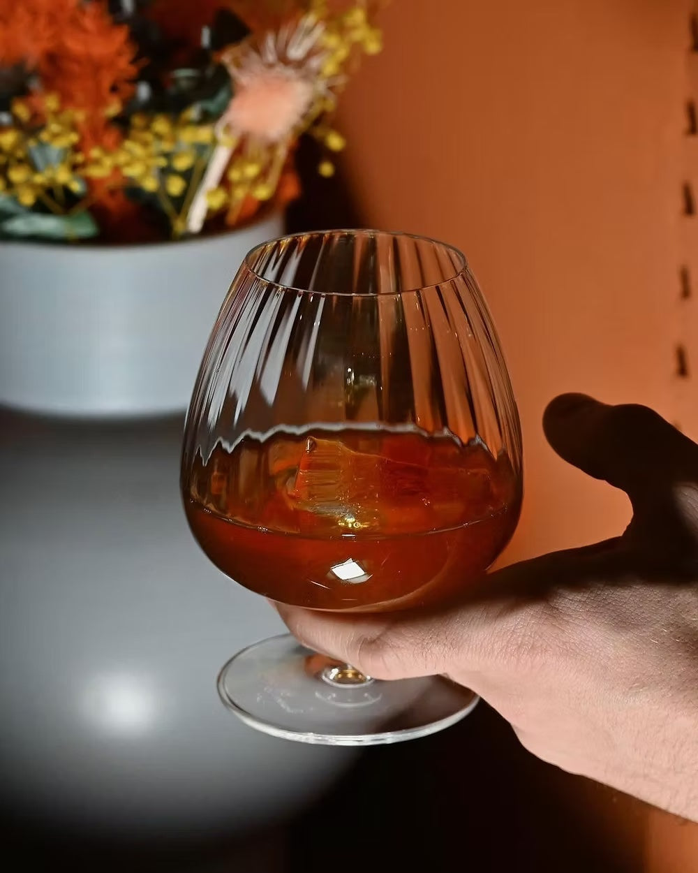Holding a Luigi Bormioli cognac glass with ribbed design.