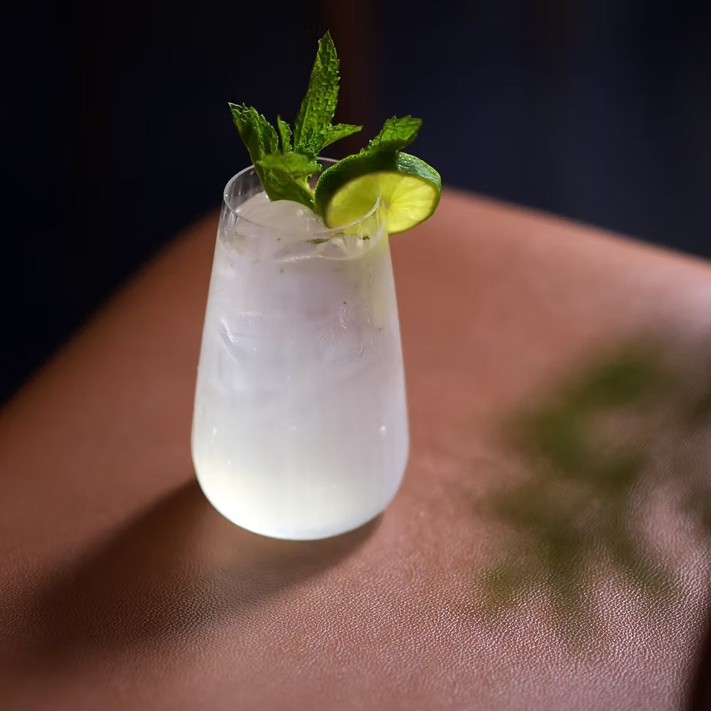 Optica fluted highball glass with lime and mint garnish, filled with drink.