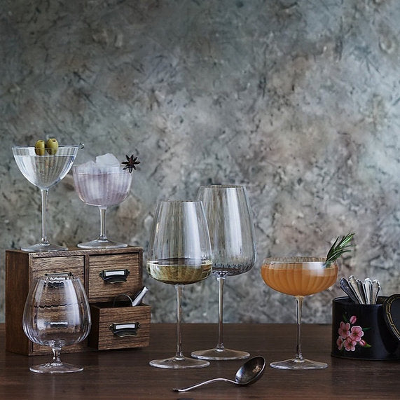 Luigi Bormioli set with fluted white wine glasses on a wooden table.