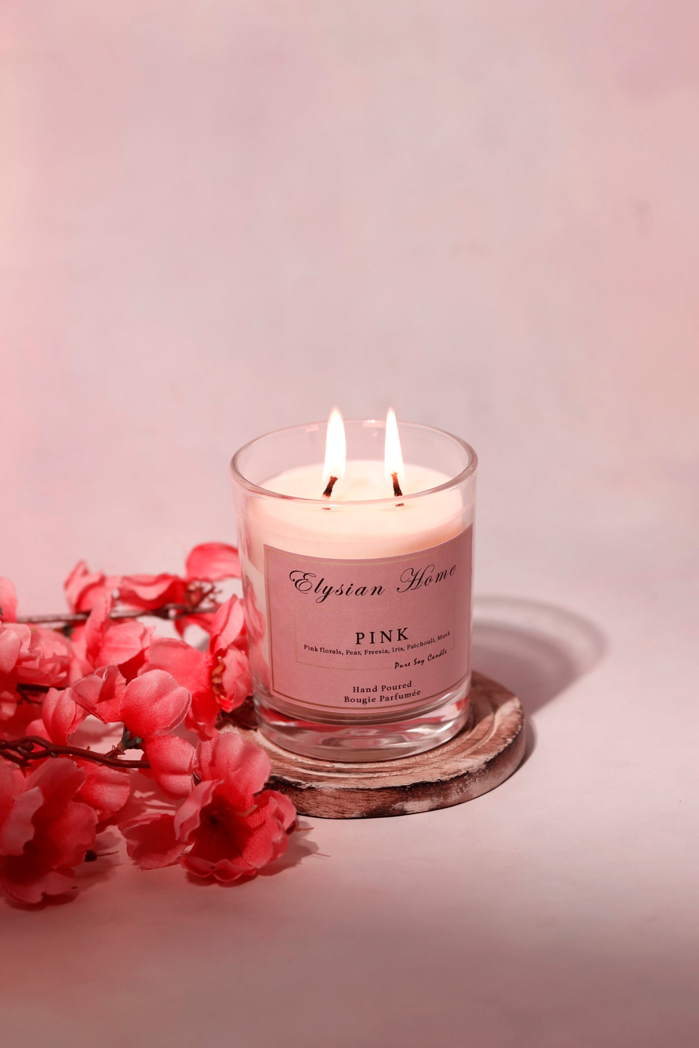 Burning floral candle with pink accents and wooden coaster