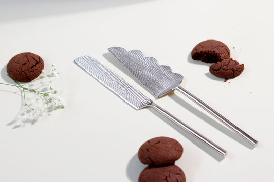 Silver cake server and knife set with linear design, ready for dessert.