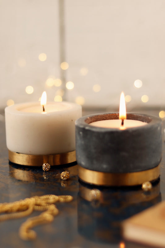 Lit marble candle set with gold base and decorative beads.