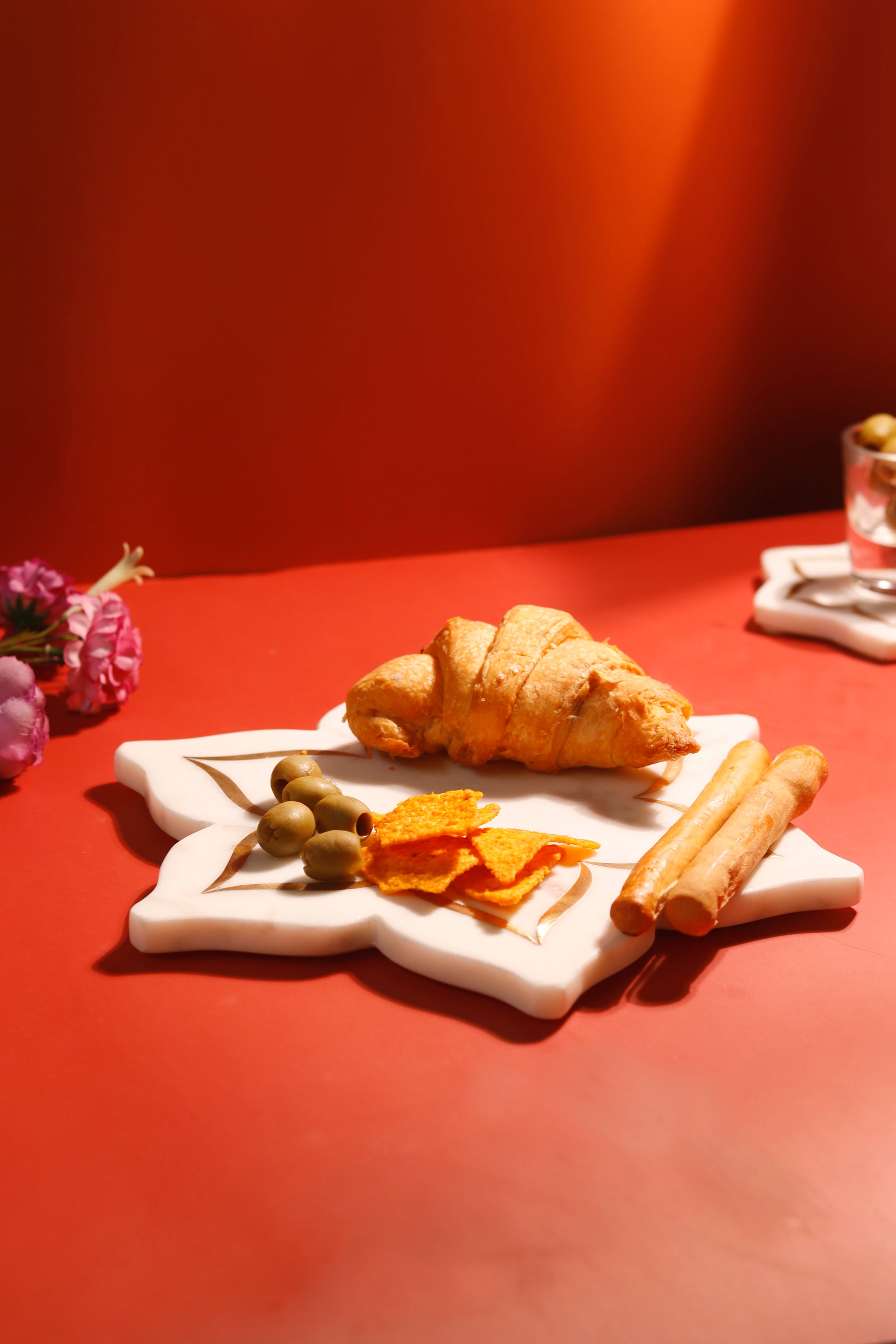 Lotus platter with brass inlay holding croissant, olives and snacks.