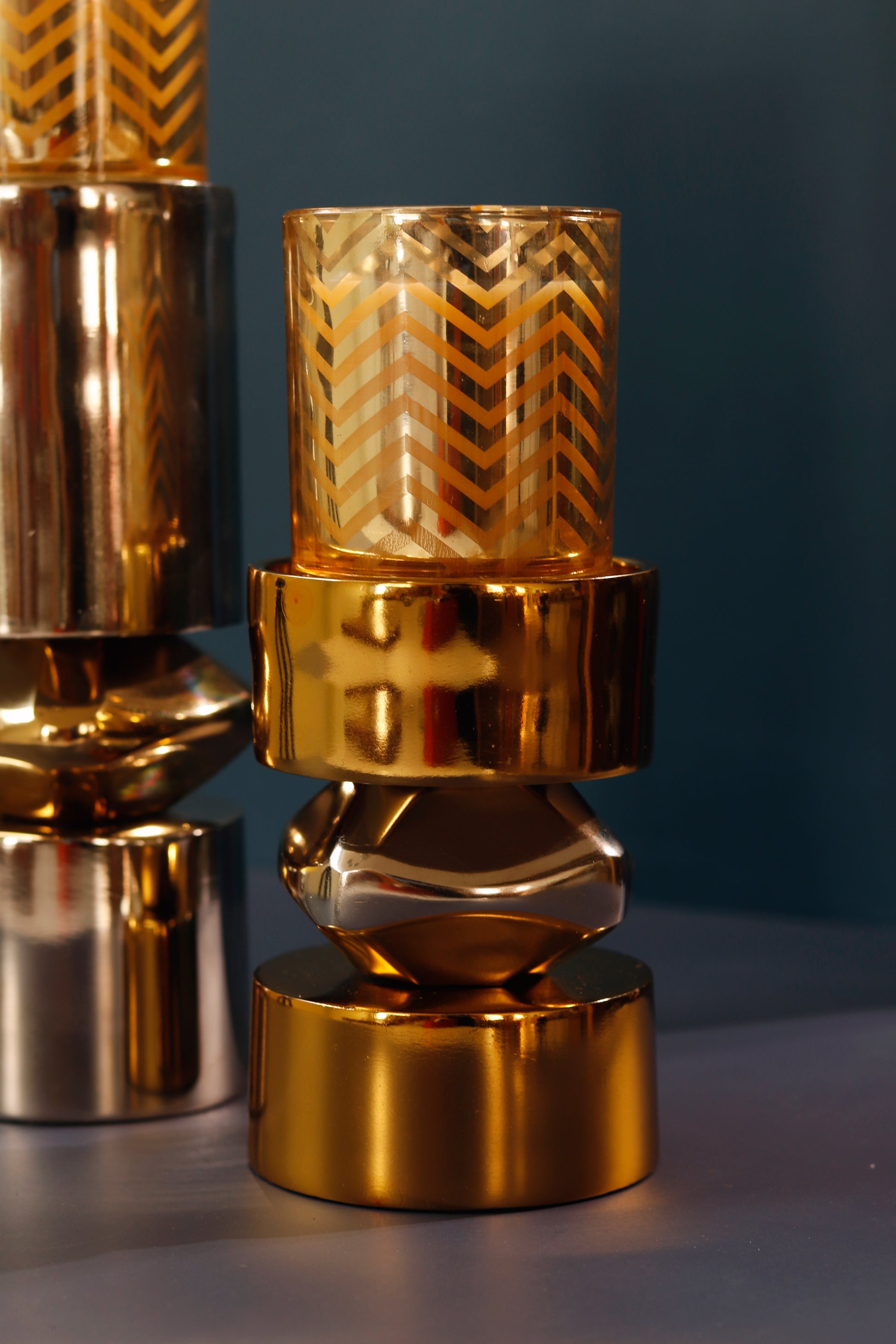 Stylish gold metal candle stand with nickel accents and geometric design.
