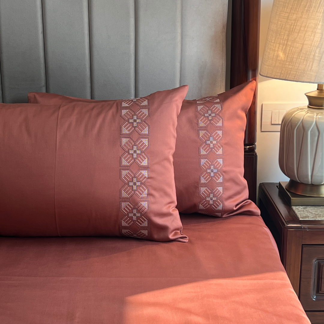 Terracotta bedsheet with embroidered pillow covers styled on bed