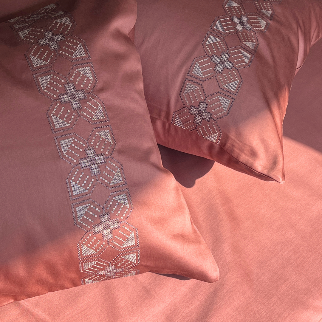 Close-up of embroidered pillow cover detail in terracotta tone
