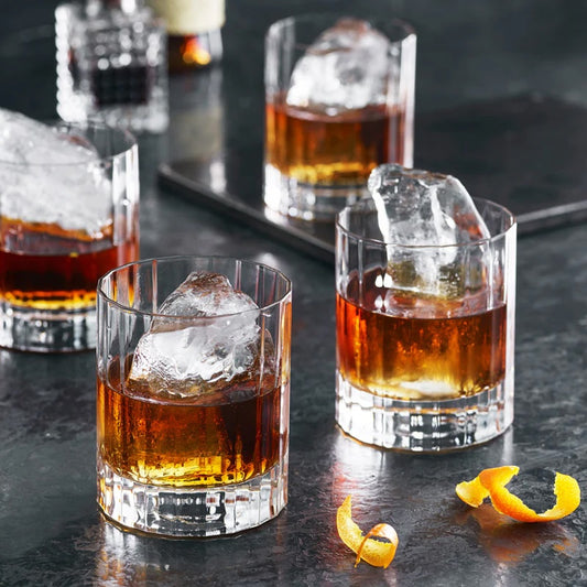Set of six old fashioned glass tumblers with ice and orange peel garnish
