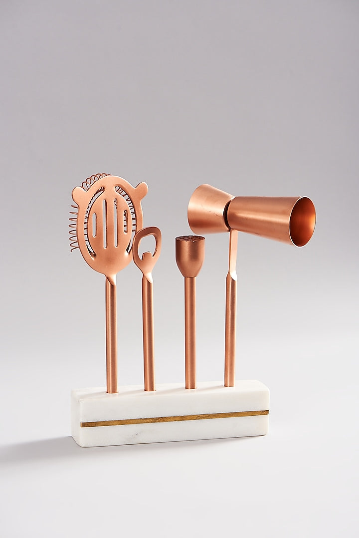 Copper bar accessories with a stylish marble stand for a modern bar setup.