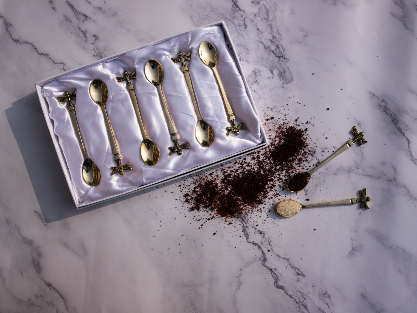 Golden tea spoon set with bee handle detail.