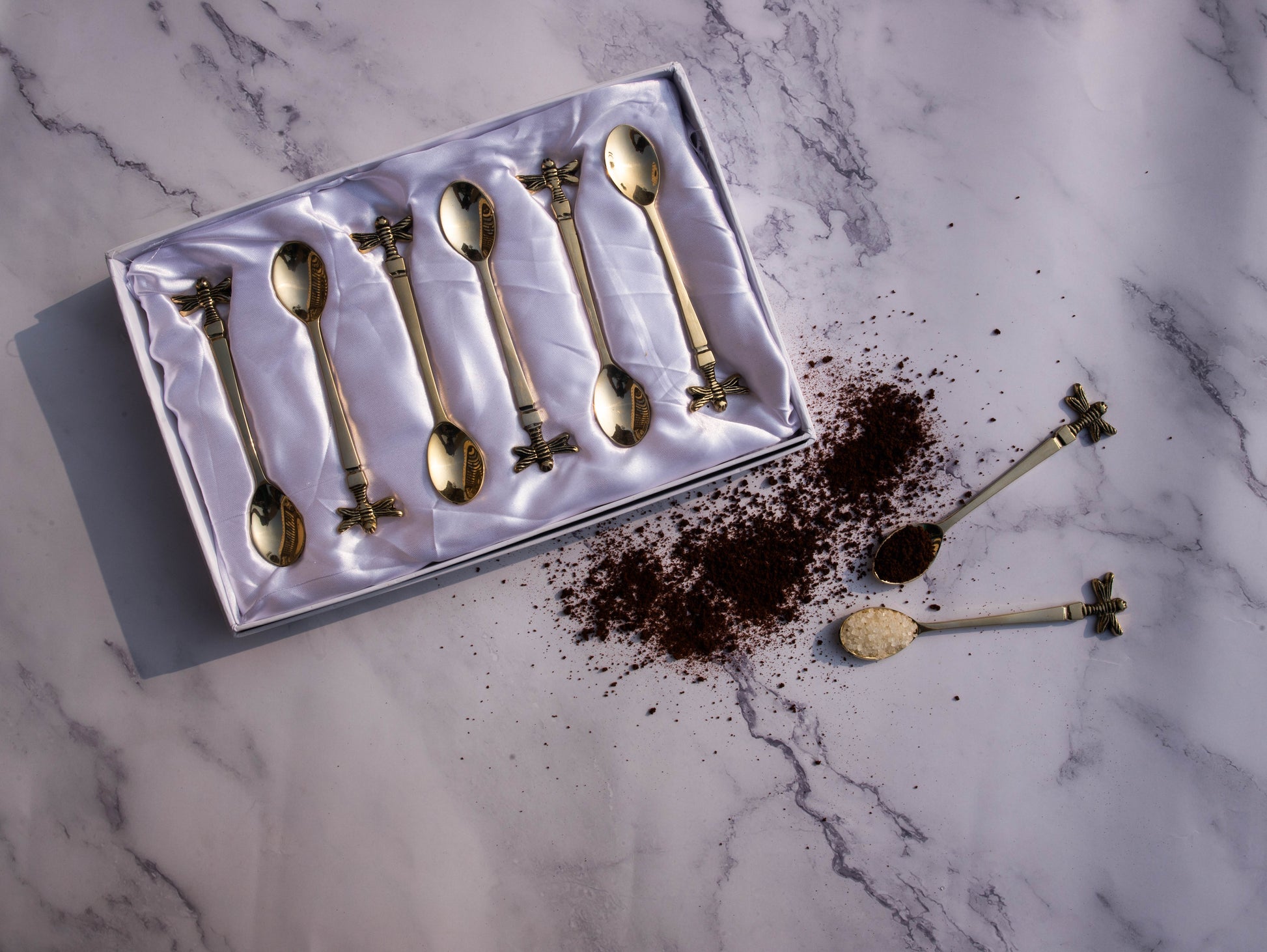 Golden tea spoon set with bee handle detail.