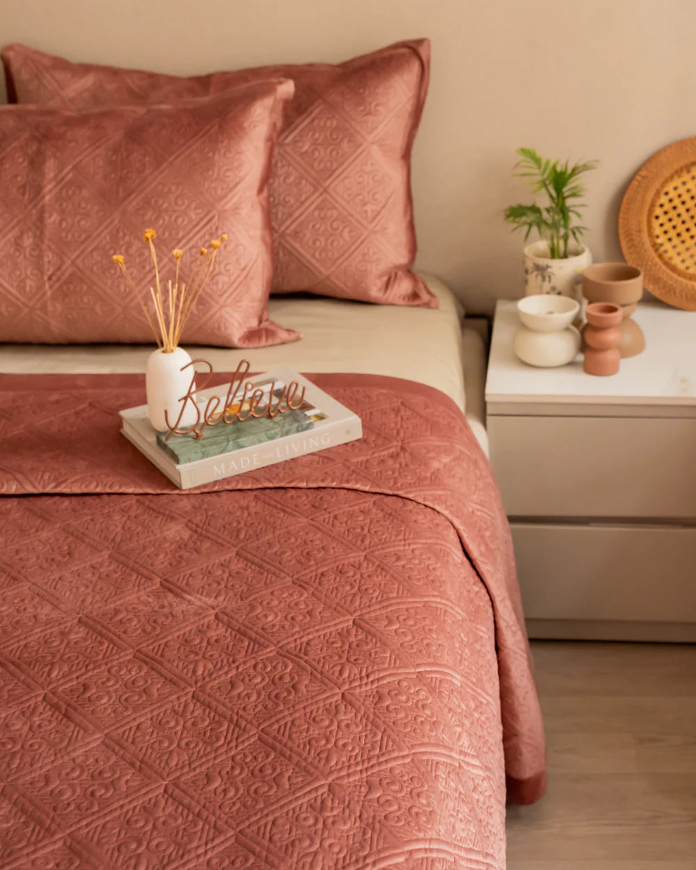 Blush velvet bedspread with a quilted pattern and matching pillows.