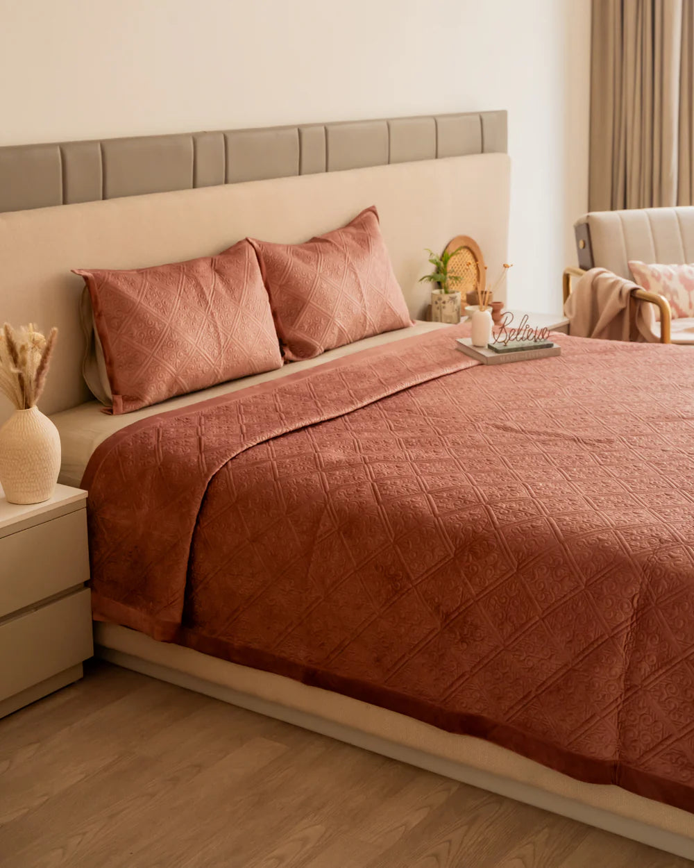 Blush velvet bedspread with quilted pattern and matching pillow shams.
