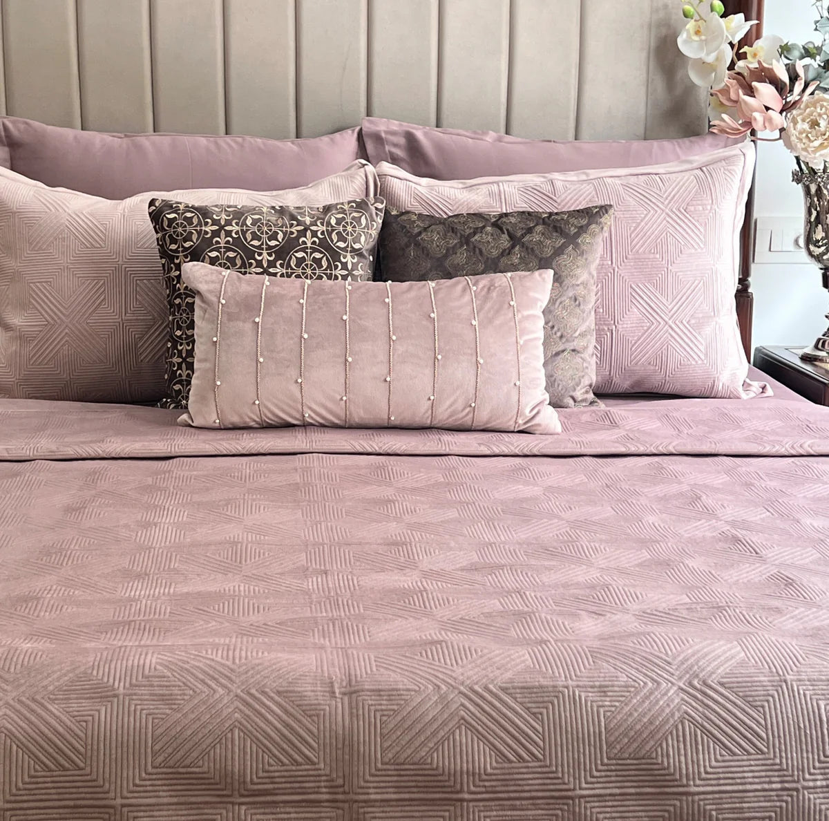 Onion pink velvet bedspread with geometric design and matching pillows.