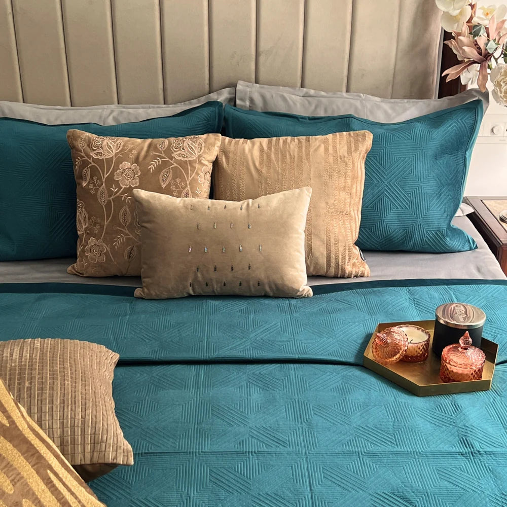 Emerald green velvet bedspread with geometric pattern and pillows.