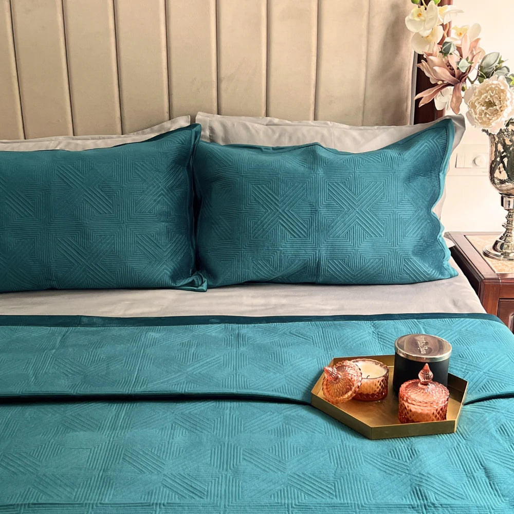 Emerald green velvet bedspread with geometric pattern and matching pillows.