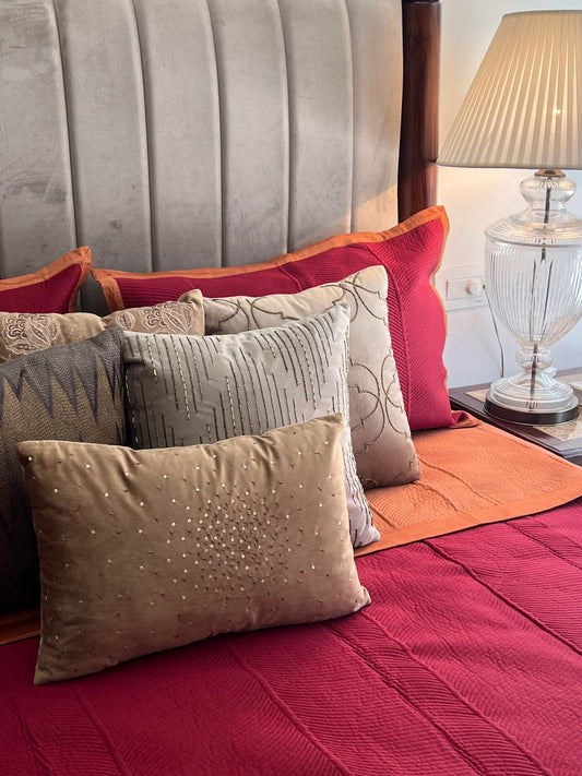 Maroon cotton bedspread with rosette pattern and decorative pillows.