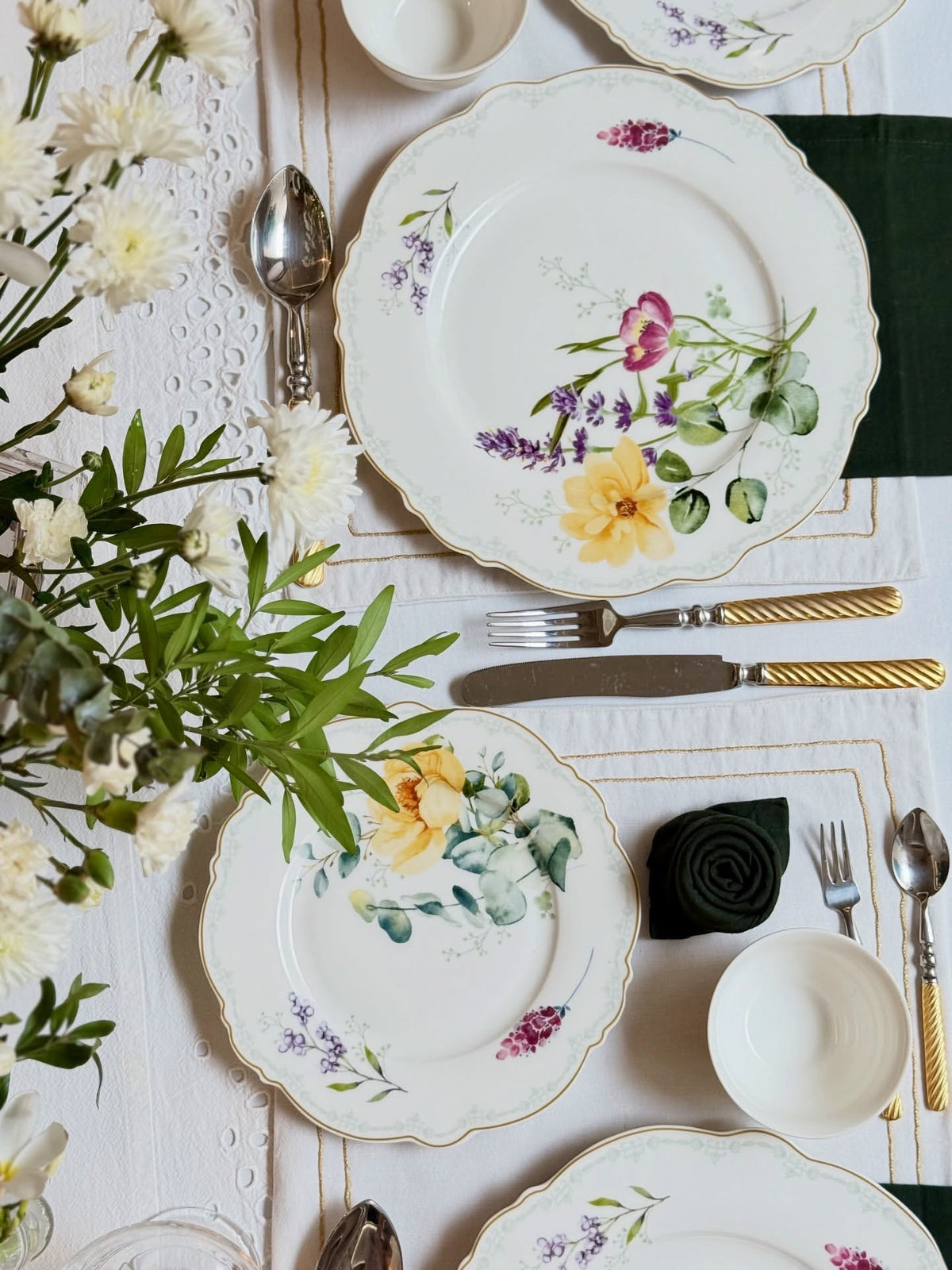 Overhead view of Eternal Bloom plates with floral design, flatware and a black napkin rose